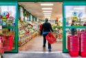 Reston, USA - December 18, 2017: Trader Joe's customer trolley shopping basket carrying carts by store entrance doors outside women, winter flower pots, gardening plants, pineapple in Virginia